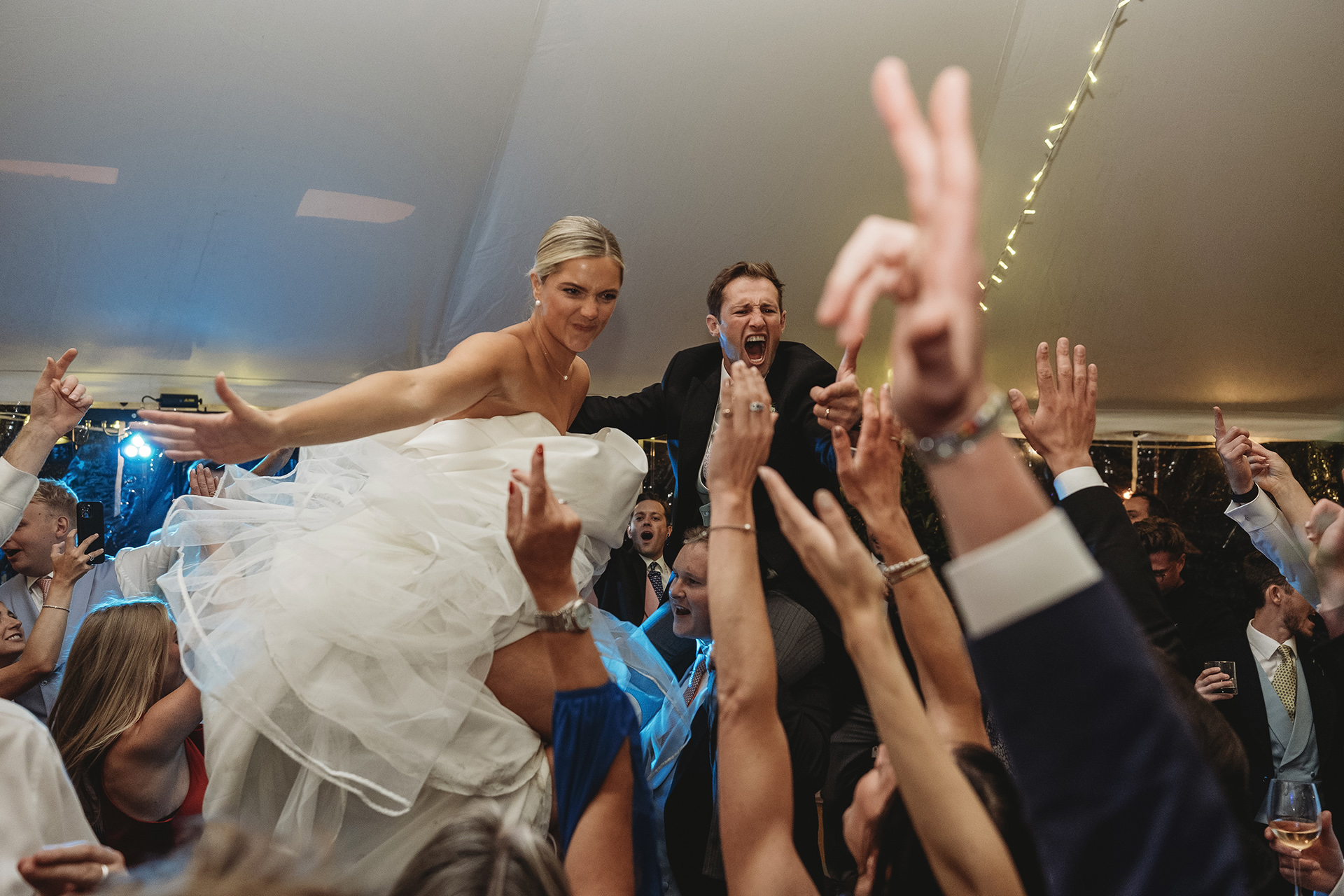 bride and groom on guests shoulders at wedding