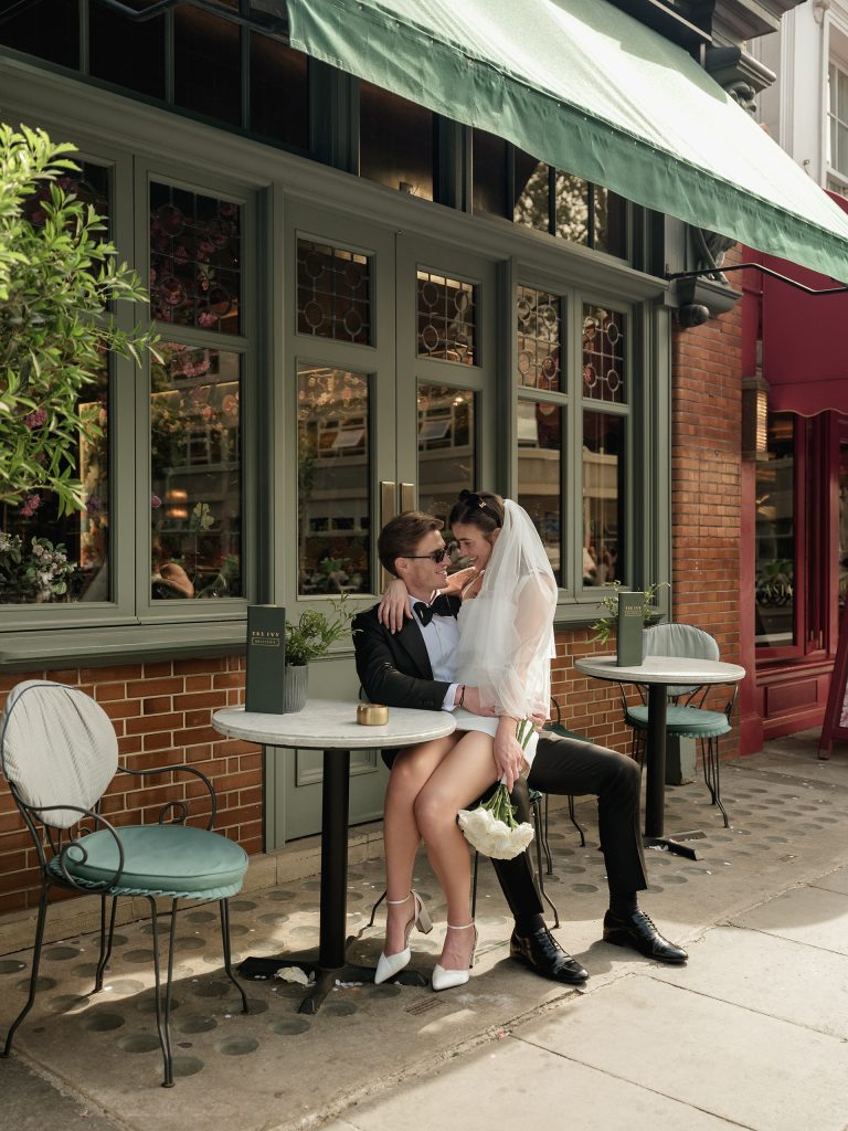Bride and groom sitting outside a café in London after their wedding ceremony