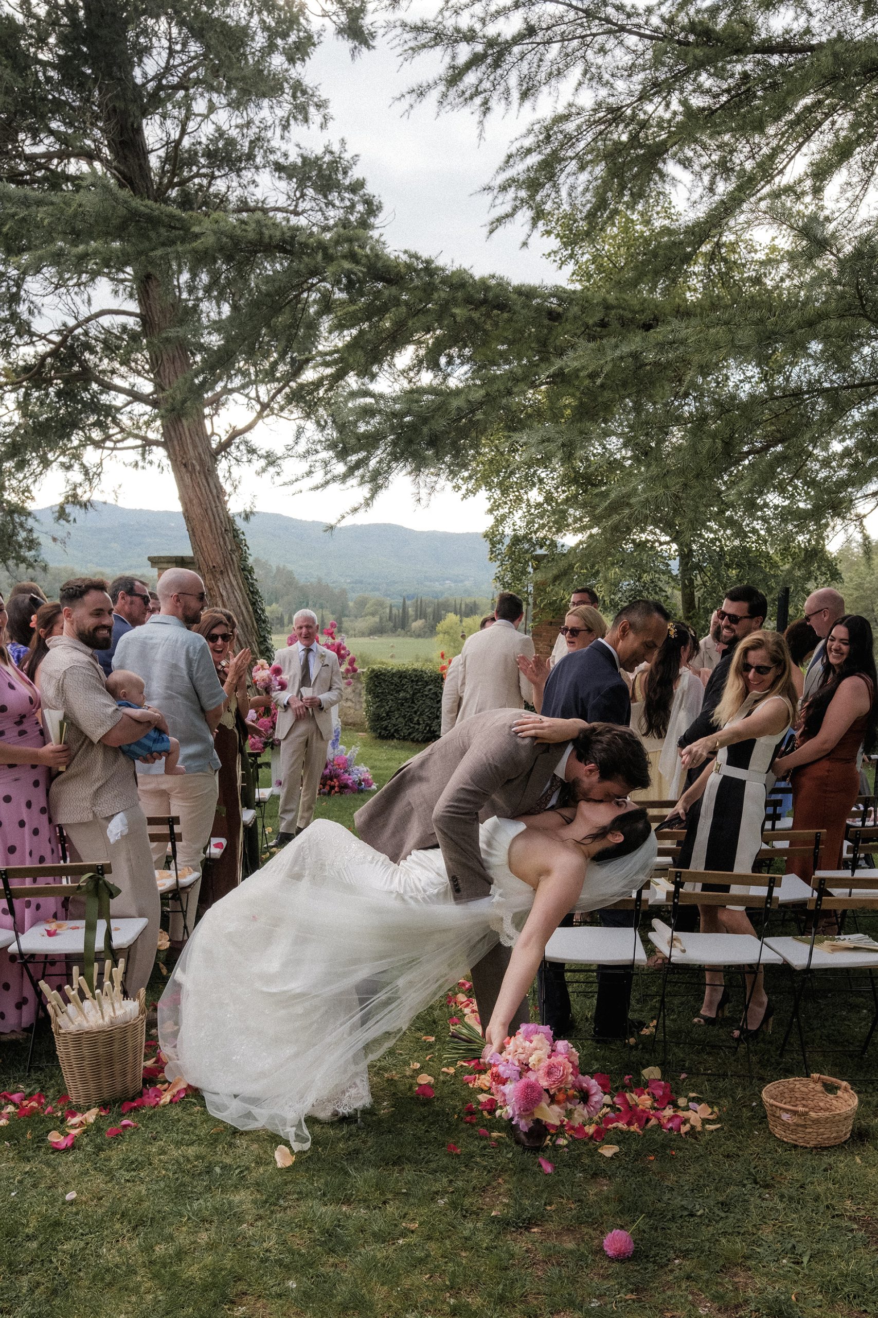 Bride and groom sharing a celebratory dip kiss after their outdoor wedding ceremony in the Tuscan countryside